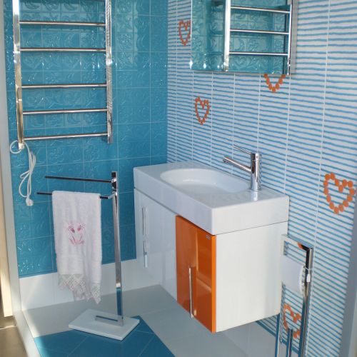 Baño completo en exposición con azulejos azules y corazones